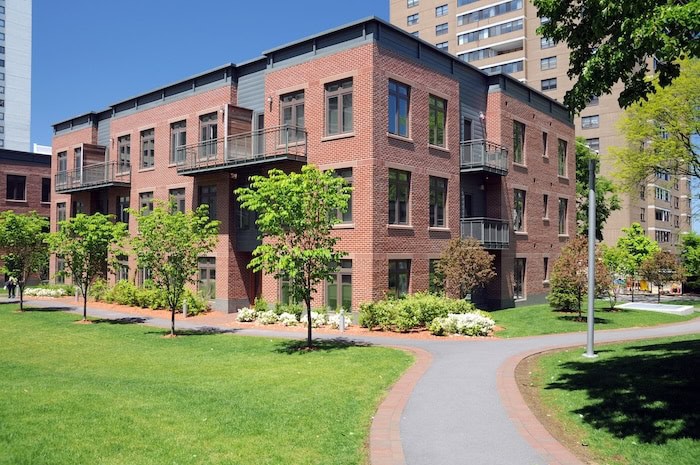 A rectangular red brick condo building with exterior common areas